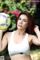 A woman in a white sports bra holding a soccer ball.