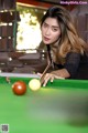 A woman leaning over a pool table with a cue.