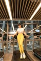 A woman in a white top and yellow leggings on a treadmill.