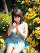 A woman in a blue dress sitting on a wooden bench surrounded by yellow flowers.