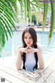 A woman sitting on a wooden deck next to a swimming pool.