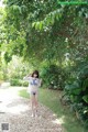 A woman in a blue bikini standing under a tree.