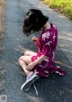 A woman sitting on the side of a road looking at her cell phone.