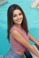 A young woman sitting on the edge of a swimming pool.