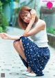 A woman sitting on the ground with her legs crossed.