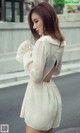 A woman in a white dress is walking down the street.