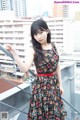 A woman in a floral dress standing on a balcony.