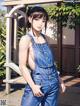 A woman in overalls is posing for a picture.