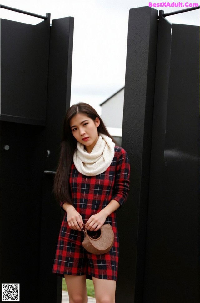 A woman wearing a red and black plaid dress and a white scarf.