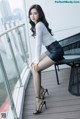 A woman sitting on top of a balcony next to a table.