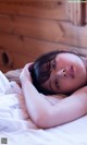 A woman laying on a bed with her head on her hands.