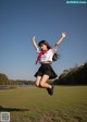 A woman in a school uniform jumping in the air.