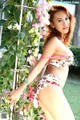 A woman in a floral bikini posing in front of flowers.