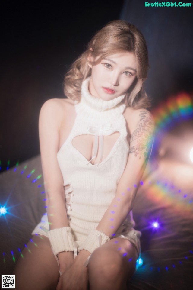 A woman in a white dress sitting on a bed.
