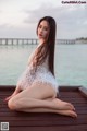 A woman sitting on a wooden dock by the water.